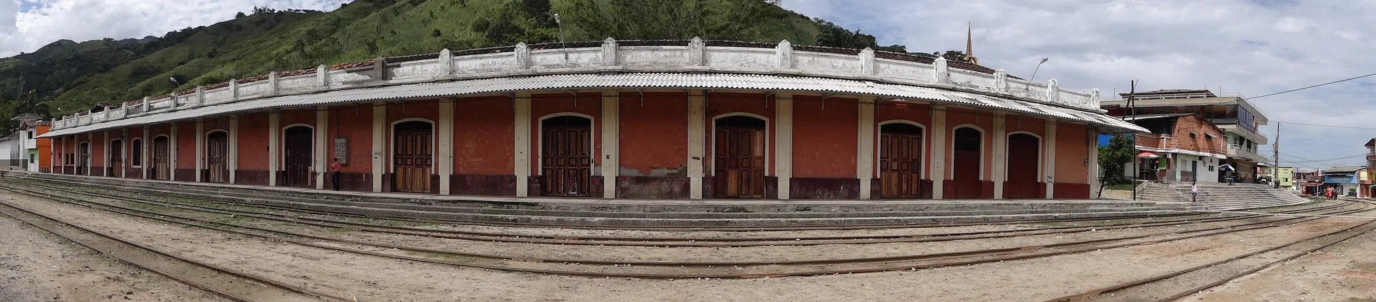 Panorámica muy apaisada de toda la fachada de la estación con las vías en primer plano.