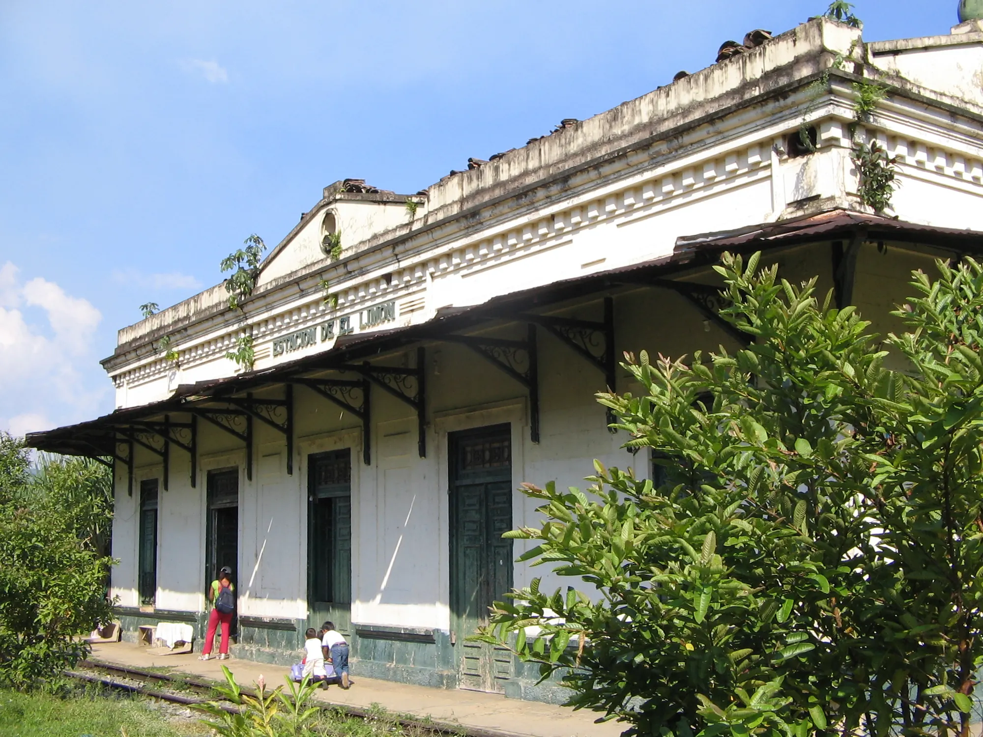Edificio de la estación El Limón con su frontón y la vegetación del andén.