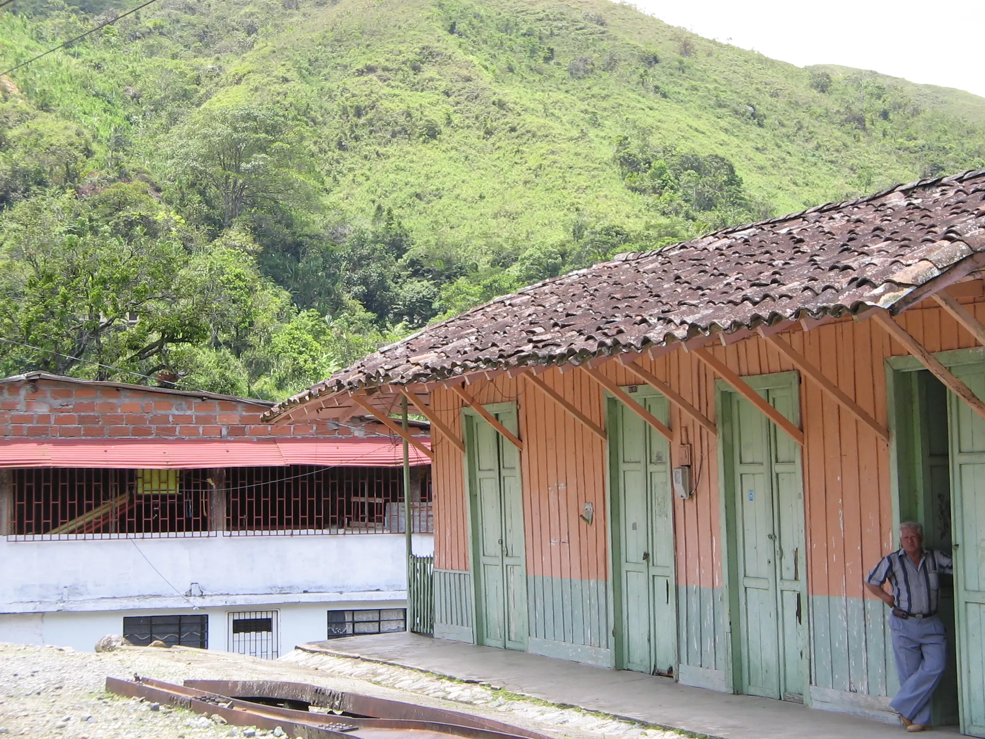 Antigua estación de Santiago con su corredor de madera; un hombre recostado en la pared.