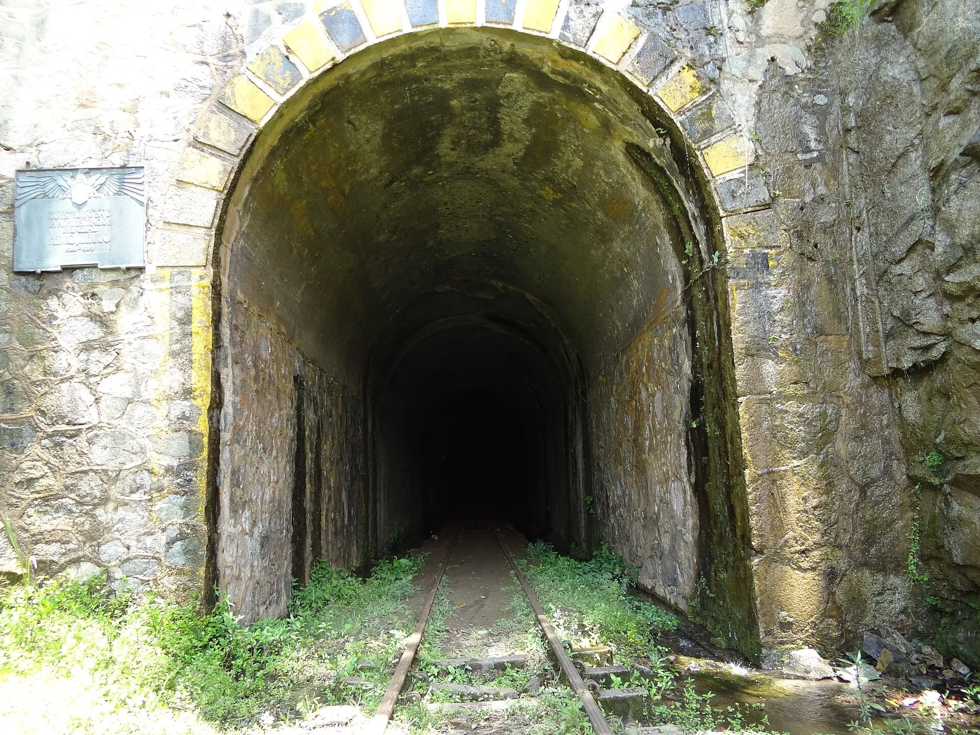 Acercamiento al portal de Santiago: arco, mampostería y rieles que se pierden en la oscuridad.