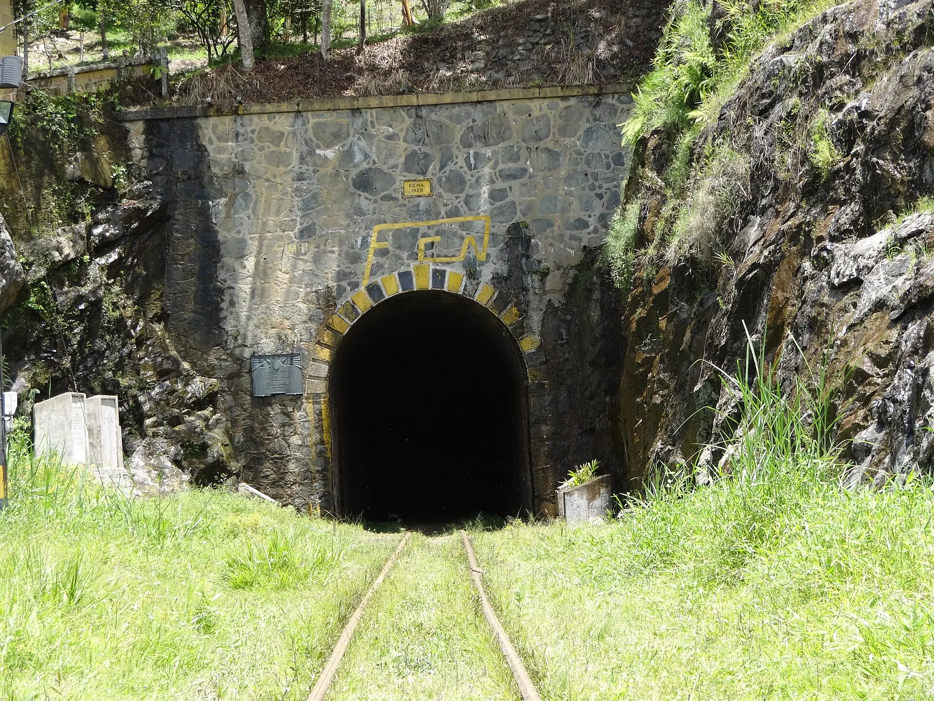 Boca occidental del túnel en Santiago (Santo Domingo): portal de piedra con el escudo y la vía férrea.